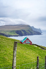 Fototapeta na wymiar Dramatic scenery of Mikynes Island, Faroe Islands. Landscape of giant sea cliffs overlooking the ocean at Mykines, Faroe Islands.
