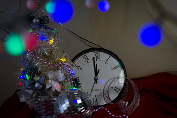 Fototapeta na wymiar Happy New Year 2020. Christmas decorations with a clock of a Christmas fir tree on the background of lights and tinsel..