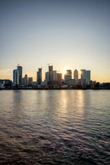 Fototapeta na wymiar Blick über die Themse auf die Hochhäuser des Bezirkes Canary Wharf in London zum Sonnenuntergang