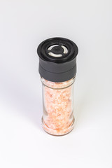 Himalayan salt crystals in a glass grinder on white background