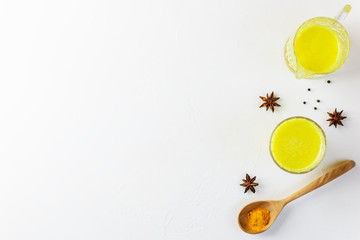 Golden milk from turmeric, vegetable milk, pepper, ginger, coconut oil, maple syrup in a glass on a white background. Traditional indian drink, copy space.