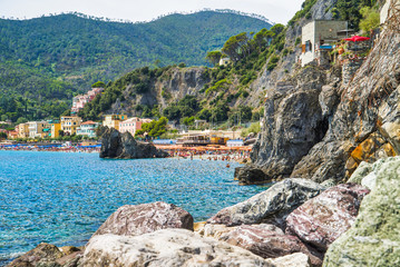 Fototapeta na wymiar Monterosso al Mare, Cinque Terre, Italy - August 17, 2019: Boats on the pier, houses on the hill, city view / City beach on the sea coast