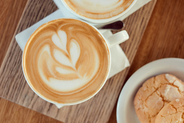 Morning coffee lifestyle. Cup of cappuccino with cookies on a wooden table.