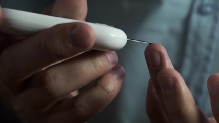 Diabetes man at home checking their blood sugar with diabetic blood sugar test kit, close up