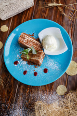 Ice cream ball and pieces of cake on a blue plate on a wooden background