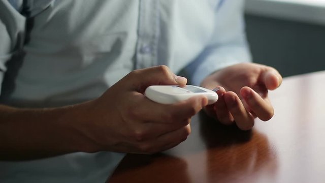 A man measures blood sugar with a glucometer, closeup