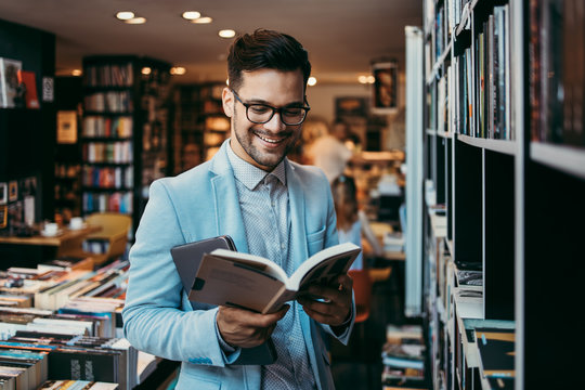 Middle age man choosing and reading books in modern bookstore.