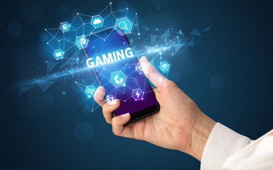 Female hand holding smartphone with GAMING inscription, modern technology concept