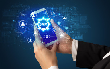 Female hand holding smartphone with SMM abbreviation, modern technology concept