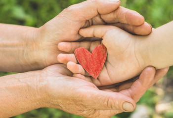Childs hand and old hand grandmother hold heart. Concept idea of love family protecting children and elderly people grandmother friendship togetherness relationship Two generation.