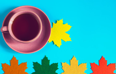 Cup of tea with decorative felt maple leaves. Top view. Autumn concept background