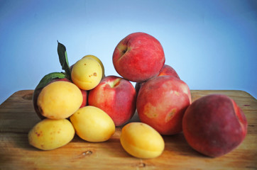 Ripe and juicy apricots and peaches with yellow and orange peels lie on a wooden table