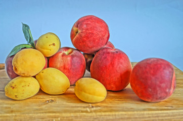 Ripe and juicy apricots and peaches with yellow and orange peels lie on a wooden table