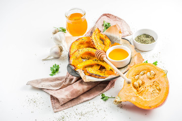 Autumn vegetarian food recipe. Organic roasted vegetables, Baked fried Hokkaido pumpkin with olive oil, herbs, garlic and honey. On a white stone background, copy space