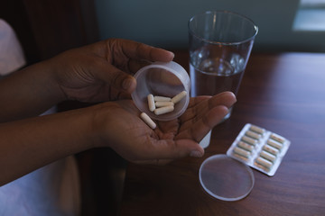 Senior woman taking medicine with glass of water in bed at home