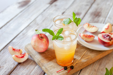 Peach cocktail with mint on white wooden background