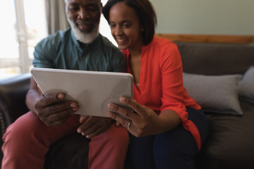 Fototapeta premium Senior couple using digital tablet in living room at home