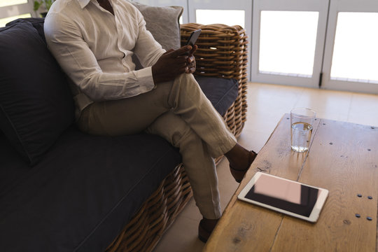 Senior man using mobile phone in living room at home