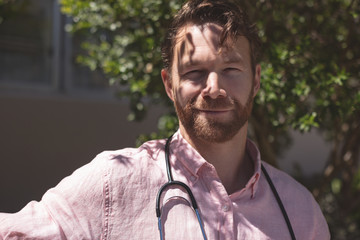 Confident male doctor sitting on bench outside the nursing home