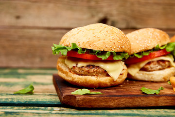 Craft beef burger  on wooden table isolated on black background..Street food, fast food. Homemade juicy burgers with cheese and  on the wooden table. Copy space.