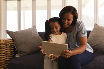 Fototapeta premium Mother and daughter using digital tablet in living room