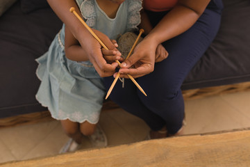 Obraz na płótnie Canvas Grandmother teaching her granddaughter how to knitt in living room