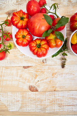 Mix of tomatoes background. Beautiful juicy organic red tomatoes on white wooden table background. Clean eating concept. Copy space, flat lay..
