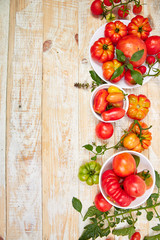 Mix of tomatoes background. Beautiful juicy organic red tomatoes on white wooden table background. Clean eating concept. Copy space, flat lay..