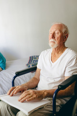 Blind senior man using braille to read in a retirement home