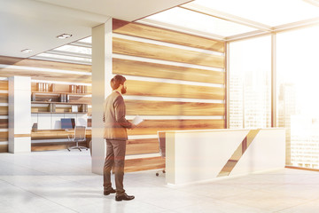 Man in white and wooden office with reception