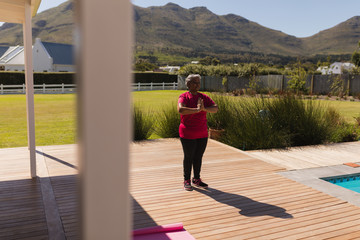Obraz premium Senior woman performing yoga in the backyard of home
