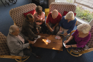 Group of senior friends playing cards at nursing home