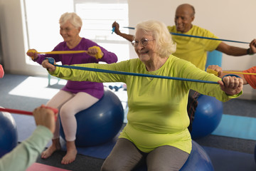 Senior people exercising with resistance band in fitness studio