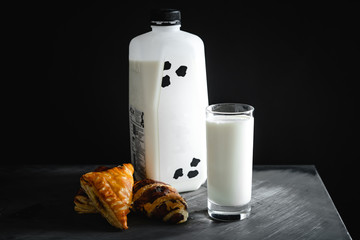 Milk in a glass and bread in a dark scene