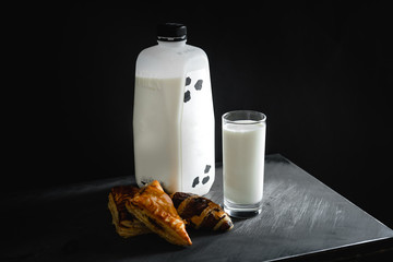 Milk in a glass and bread in a dark scene