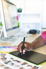 Graphic designer working on graphic tablet at desk 