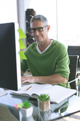 Happy businessman working on computer at desk in office