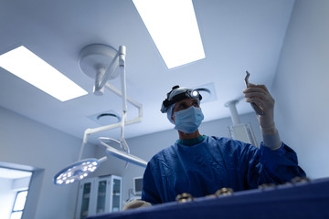 Female surgeon with surgical instrument in operation theater