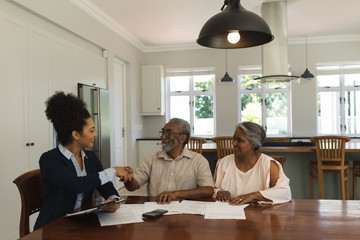 Female real estate agent shaking hands with senior man