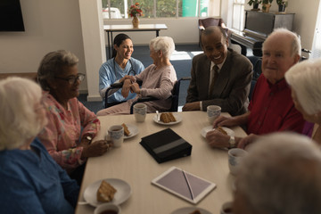 Group of senior friends having breakfast on dining table at nursing home