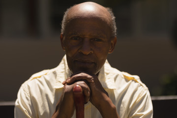 Front view of senior man hands leaning on a cane while sitting on bench