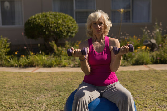 Senior woman exercising with dumbbells in the park