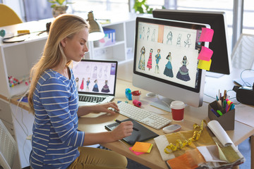 Female fashion designer using graphic tablet while working at desk 