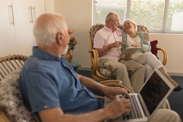 Obraz premium Senior man using laptop while senor couple using digital tablet at nursing home
