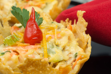 Parmesan cheese basket stufed with chicken salad and pout pepper in black background close