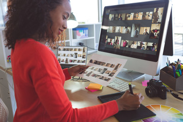 Female graphic designer writing at desk