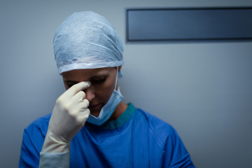 Fototapeta na wymiar Upset female surgeon standing while leaning against the operating room door