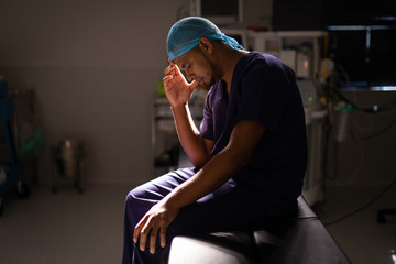 Nervous male surgeon sitting in operation room at hospital