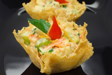 Parmesan cheese basket stufed with chicken salad and pout pepper in black background