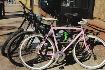 Fototapeta na wymiar Two black and a pink bicycle parked on city street